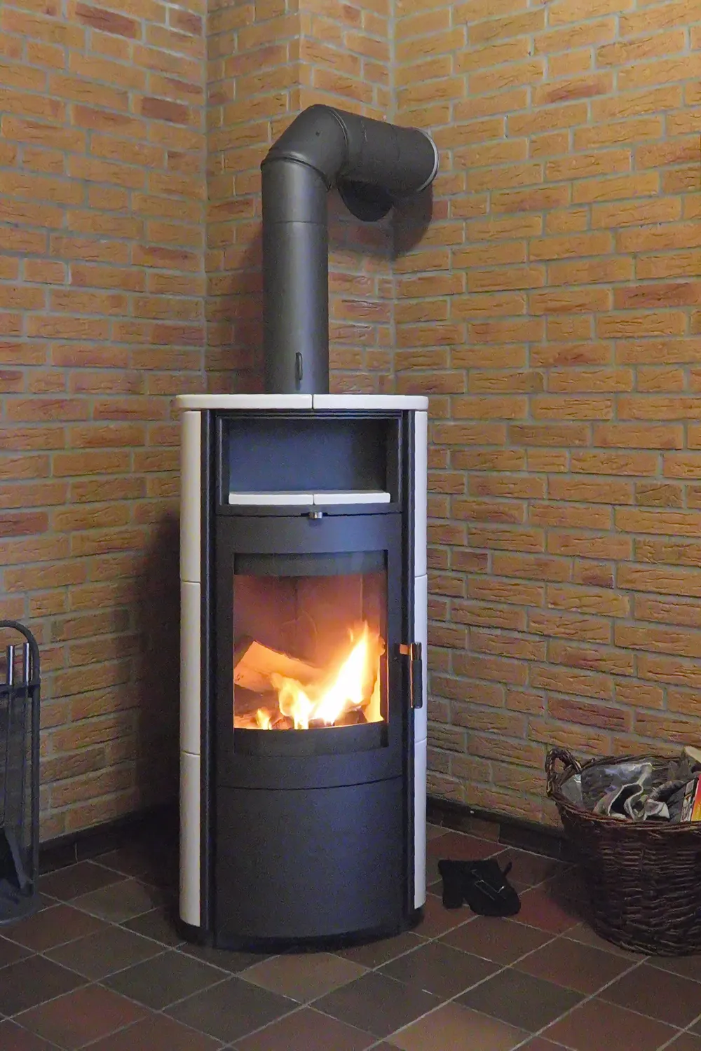 Poêle à bois moderne installé dans l'angle d'un salon, conduit de fumée apparent